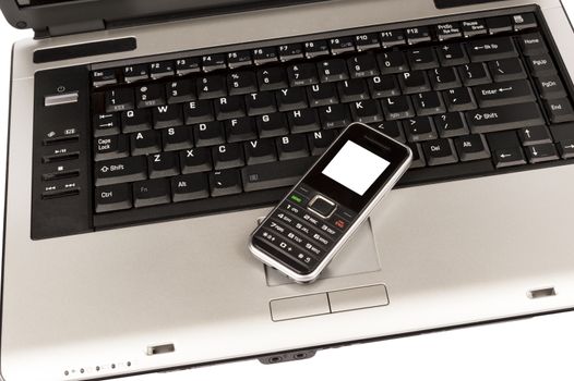 Close up of mobile phone resting on keyboard of laptop.  Isolated on white background.