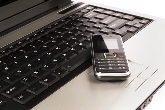 Close up of a mobile phone on a laptop keyboard.