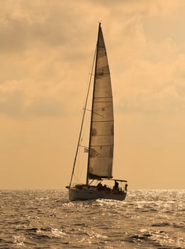 Yacht sailing against sunset. Lonely sail in the evening