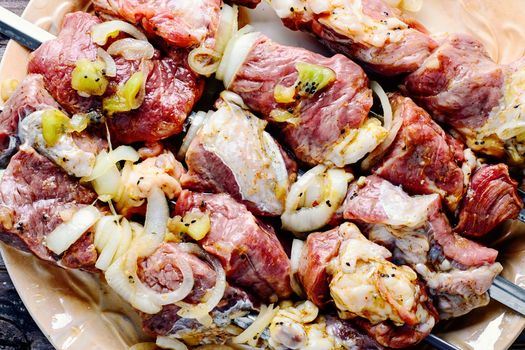 Meat in the spices and marinade with kiwi threaded on skewers for kebabs