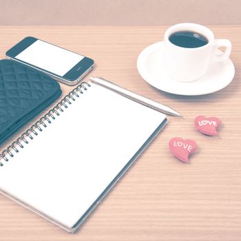 working table : coffee with phone,notepad,wallet and red heart on wood background vintage style