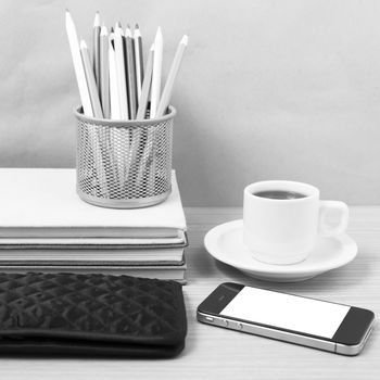 office desk : coffee with phone,stack of book,wallet,color box on wood background black and white color