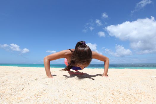 Beautiful young woman doing workout on tropical beach