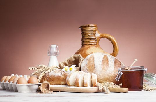 Freshly baked bread,honey and eggs on wooden vintage table