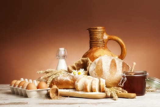 Freshly baked bread,honey and eggs on wooden vintage table