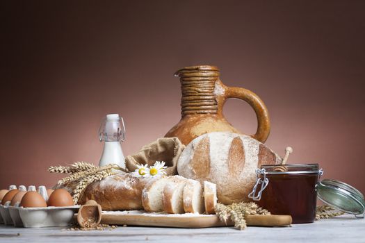 Freshly baked bread,honey and eggs on wooden vintage table