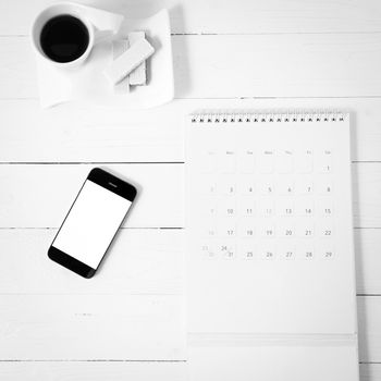 coffee cup with wafer,phone,calendar on white wood background black and white color