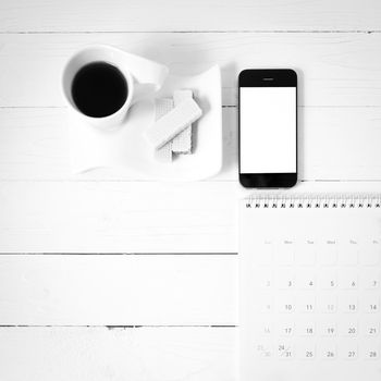 coffee cup with wafer,phone,calendar on white wood background black and white color