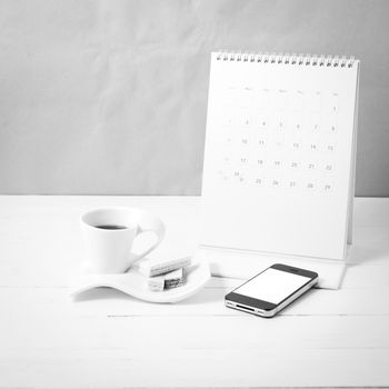 coffee cup with wafer,phone,calendar on white wood background black and white color