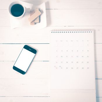 coffee cup with wafer,phone,calendar on white wood background vintage style