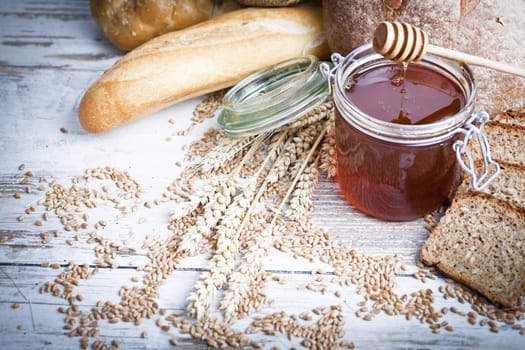 Freshly baked bread rolls, wheat ears and honey