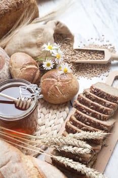 Freshly baked bread rolls, wheat ears and honey