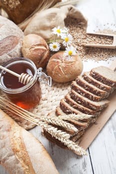 Freshly baked bread rolls, wheat ears and honey