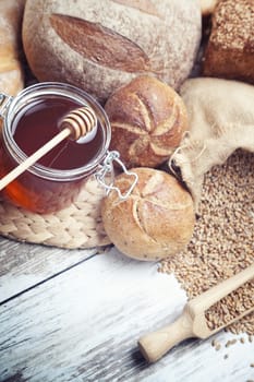 Freshly baked bread rolls, wheat ears and honey