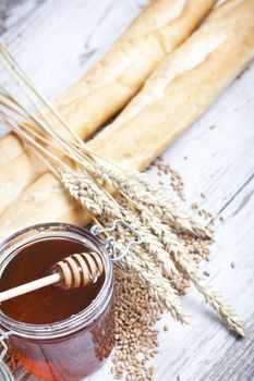 Freshly baked bread rolls, wheat ears and honey