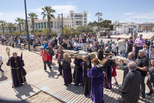 SPAIN, Valencia: Onlookers watch and take pictures of penitents of the “Cristo Salvador y del Amparo” (Christ the Saviour and Protector) brotherhood walking by during the Good Friday procession on Malvarrosa beach, in Valencia, on March 25, 2016. Christian believers around the world mark the Holy Week of Easter in celebration of the crucifixion and resurrection of Jesus Christ.