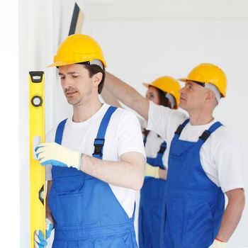 Building teamwork concept - group of smiling builders in hardhats with tools indoors