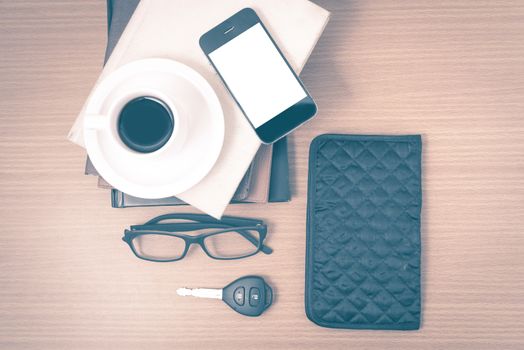 coffee and phone with stack of book,car key,eyeglasses and wallet on wood background vintage style