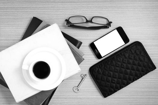 coffee and phone with stack of book,key,eyeglasses and wallet on wood background black and white color