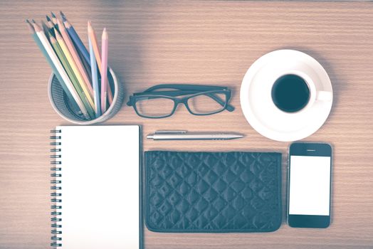 office desk : coffee with phone,notepad,eyeglasses,wallet,color pencil box on wood background vintage style