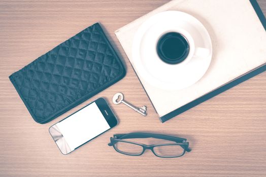 coffee and phone with stack of book,key,eyeglasses and wallet on wood background vintage style