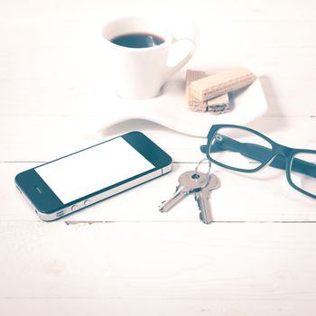 coffee cup with wafer,phone,key,eyeglasses on white wood background vintage style