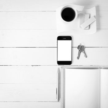 coffee cup with wafer,phone,key,notebook on white wood background black and white color