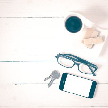 coffee cup with wafer,phone,key,eyeglasses on white wood background vintage style