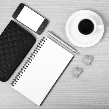 working table : coffee with phone,notepad,wallet and red heart on wood background black and white color