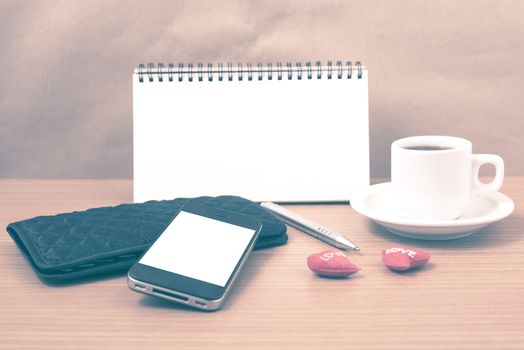 working table : coffee with phone,notepad,wallet and red heart on wood background vintage style