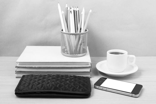 office desk : coffee with phone,stack of book,wallet,color box on wood background black and white color