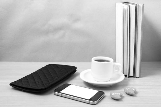 office desk : coffee with phone,heart,stack of book,wallet on wood background black and white color