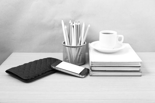 office desk : coffee with phone,stack of book,wallet,color box on wood background black and white color