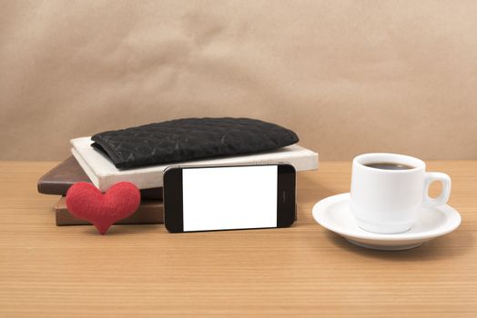 working table : coffee with phone,stack of book,wallet and heart on wood background