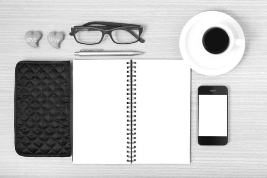 office desk : coffee with phone,notepad,eyeglasses,wallet,heart on wood background black and white color