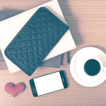 working table : coffee with phone,stack of book,wallet and heart on wood background vintage style