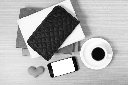 working table : coffee with phone,stack of book,wallet and heart on wood background black and white color