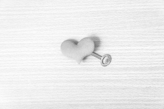 red heart with key on wood table background black and white color