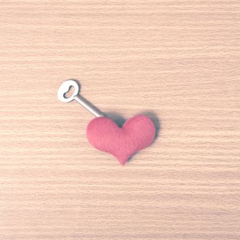 red heart with key on wood table background vintage style