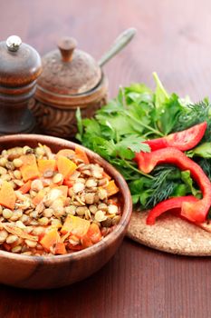 Nice wooden bowl with lentil near vegetables and seasoning