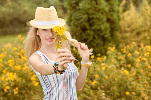 Beauty playful woman relax in summer garden smiling, people, outdoors, bokeh. Attractive happy blonde girl in hat with flower enjoying nature, harmony on meadow, lifestyle. Sunny day, forest,copyspace