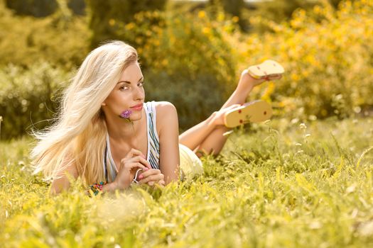 Beauty playful woman relax in summer garden smiling on grass, people, outdoors, bokeh. Attractive happy blonde girl enjoying nature, harmony on meadow, lifestyle. Sunny day, forest, flowers, copyspace