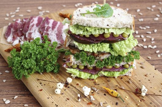 A large energy-boosting sandwich with vegetables, ham and bread with seeds