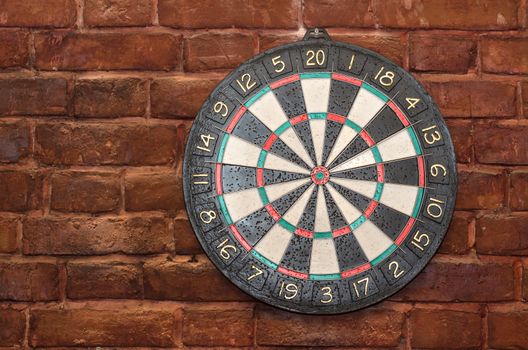 The game of Darts, hanging on the background of old brown brick wall. It played a lot.