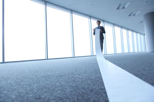 Office worker unrolling long sheet of paper