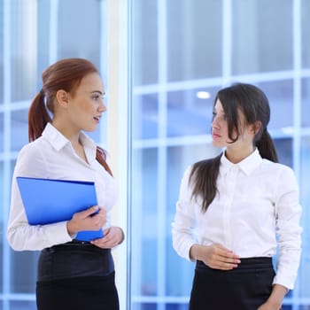 Two young beautiful businesswomen having meeting in modern office