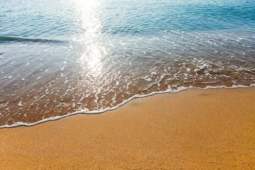 Sun light reflected on soft wave of the sea on the sandy beach