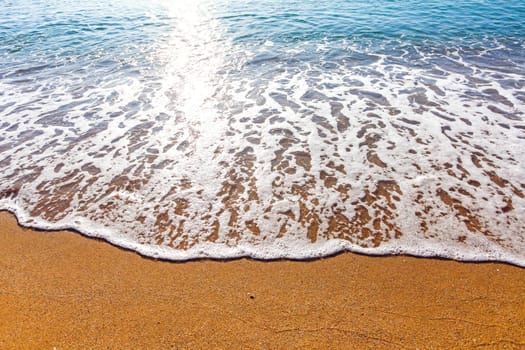 Sun light reflected on soft wave of the sea on the sandy beach