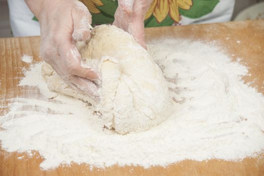 Women's hands preparing fresh yeast dough on wooden table