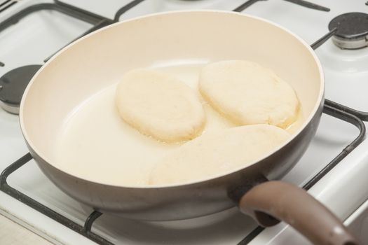 Patties with potato in the pan on the stove burning flame.